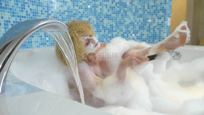 年轻美女在豪华的浴池里用浓厚的泡沫油把脚上的皮肤涂成浮石身体护理概念图片