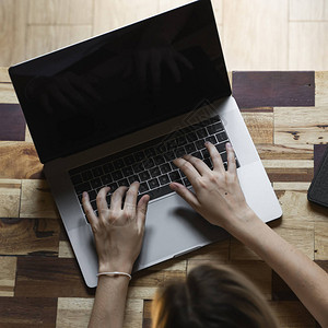 女人的手在笔记本电脑键盘顶视图上打字图片