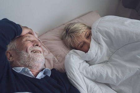 快乐的老年夫妇白种老人和女人睡在卧室的白毯上图片
