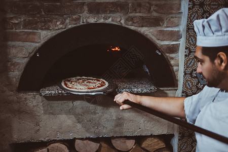 意大利厨师正把新鲜做的美食披萨图片