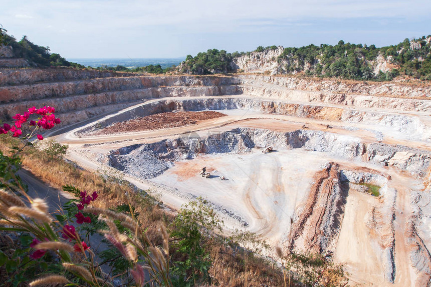 水泥采石场与工作机械的鸟瞰图岩石中露天矿和石灰岩层的奇妙景观矿区美丽的野花和浅蓝色图片