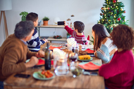 美丽的家庭微笑快乐和自信在家吃烤火鸡用智能手机自图片