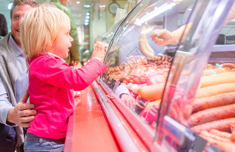 在一个超市肉柜前的小孩在看香肠的时候图片