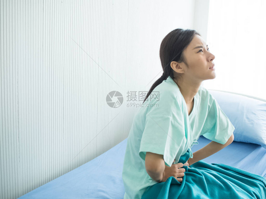 在医院病室一个坐在床上的妇女腹部疼痛头痛发烧眼图片