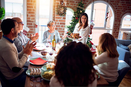 家人和朋友在家中用传统食物和装饰来庆祝圣诞节晚宴背景图片