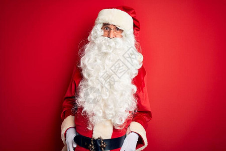 穿着圣诞老人服装的中年英俊男子站在孤立的红色背景之上图片