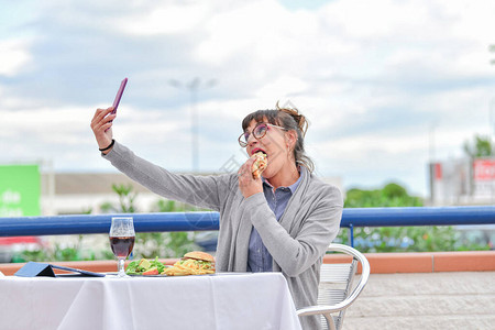 女人吃汉堡包和做自拍快餐概图片