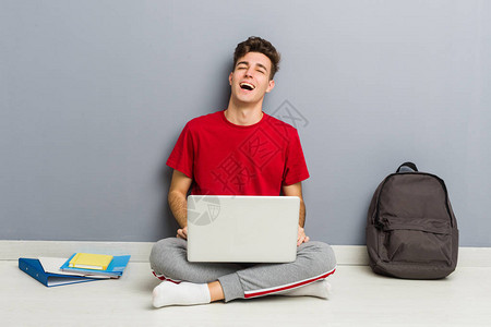青年学生男子坐在他家的地板上手图片