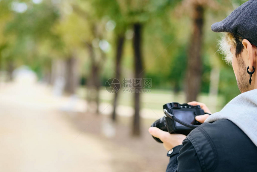 Hipster街照片摄影师在无镜相机显示公园中走着一条路的光照上回顾图片