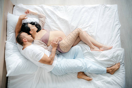 丈夫在床上睡觉时拥抱怀孕妻子图片