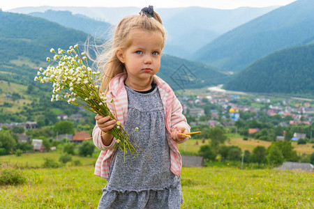 带着一束鲜花的幼女背着山跟手牵着小毛孩图片