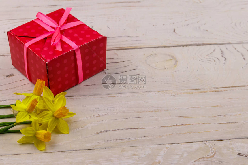 白木背景的礼品盒和黄色花水仙子情人节妇女节母亲节和生日图片