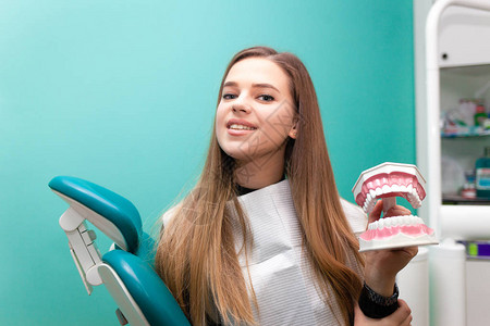 快乐的病人在下巴模型上表现出牙齿卫生临床口腔科办公室的妇图片