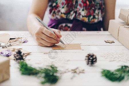 近亲手写空愿望列表和圣诞卡的女士在木制桌子上写满图片
