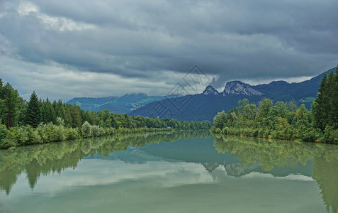 绿色的河流表面平静地反映了山岳背景图片