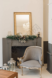 带扶手椅壁炉和镜子的灰色圣诞内饰壁炉上有圣诞树枝的垂直图片
