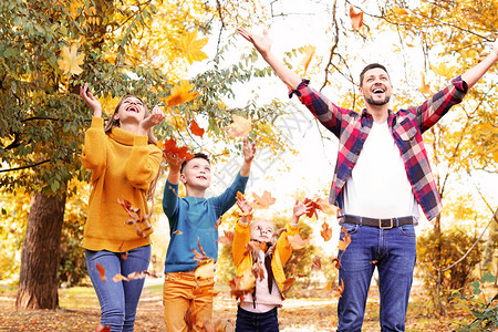 在秋季公园玩得开心的幸福家庭图片