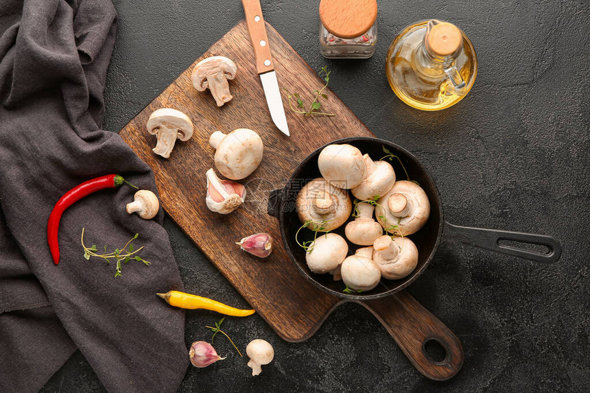 深色背景中带新鲜蘑菇香料和油的煎锅图片