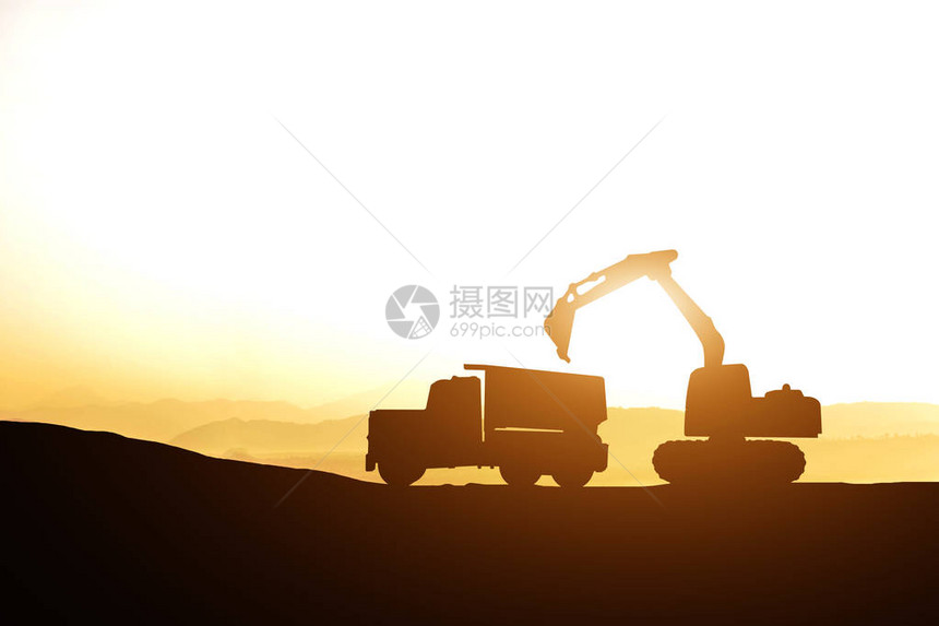 日落时施工现场挖掘机和卡车的剪影图片