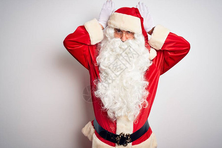 穿着圣诞老人服装的中年英俊男子站在孤立的白色背景上做耳朵手势图片