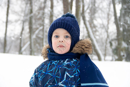 冬天在公园散步的小男孩冬季公园一个穿着冬季工作服的男孩公园里图片