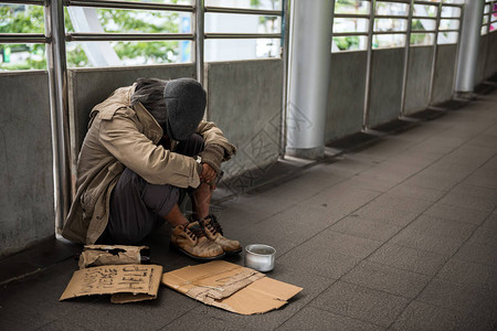 屈辱不幸无家可归的老人或乞丐低头坐在城市散步背景