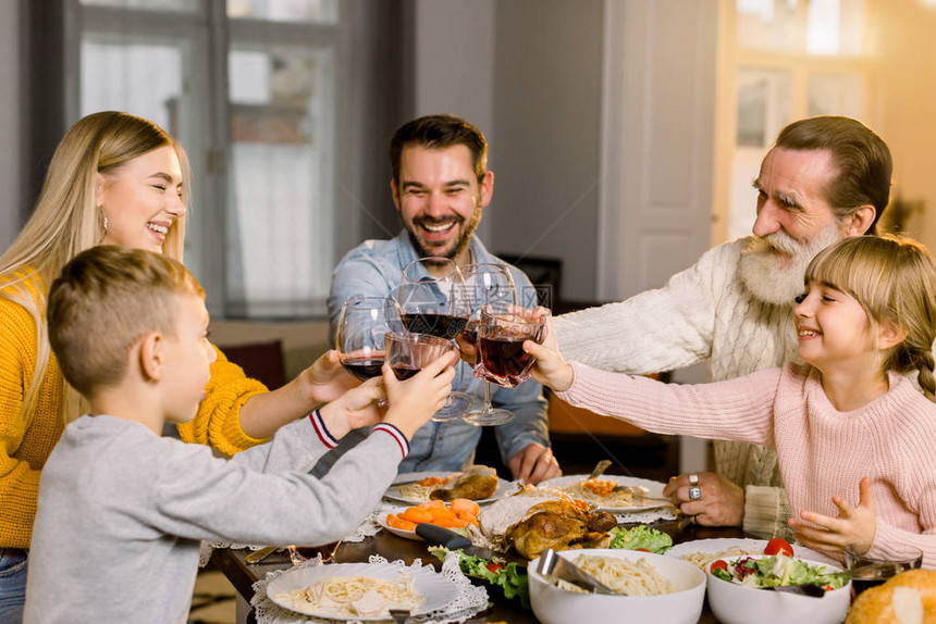 美丽幸福的家庭在节日晚餐上碰杯酒和果汁家人在家里舒适的餐厅享用美图片