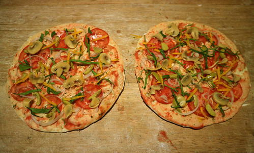 比萨饼皮在烘烤前撒上西红柿和蘑菇图片