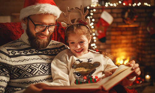 圣诞节前夜家庭父亲和孩子在家里在壁炉和圣诞树旁图片