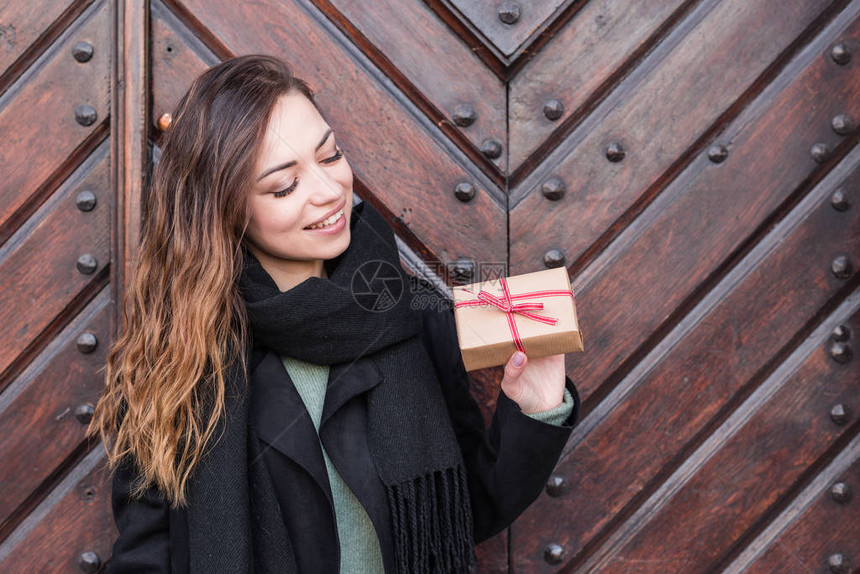 送圣诞礼物或生日礼物的女人包着棕色纸和红丝带复制空间图片