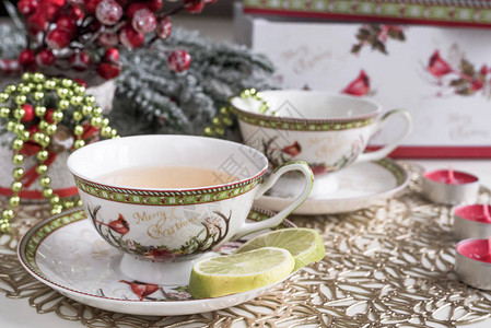 圣诞节配有鲜花白茶杯花朵和金勺子以及大龙卷风和蜡图片