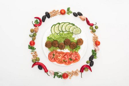 在白色背景的盘子上的falafel周围环绕圆形框排列在蔬菜顶图片