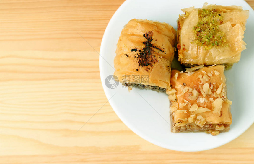 带有复制空间的木质表格上不同摊位的Baklava饼图片