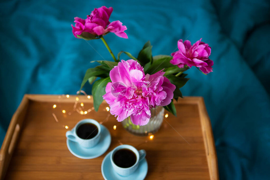 美丽的粉色红小精灵和两杯咖啡正站在床上的木盘上关闭图片