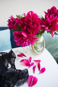 美丽的粉红色的花朵靠近窗户花瓣在桌子上碎图片