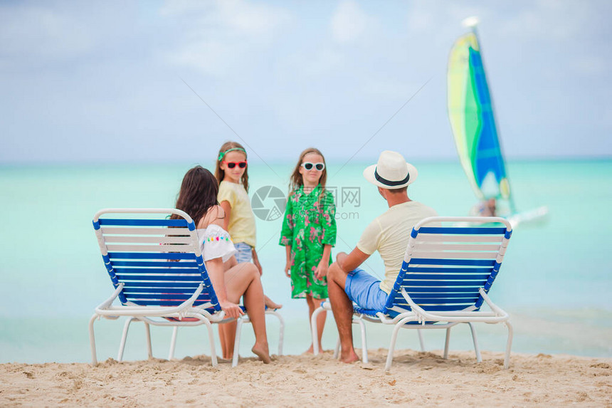海滩上美丽的家庭快乐父母和孩子在沙滩上的背图片