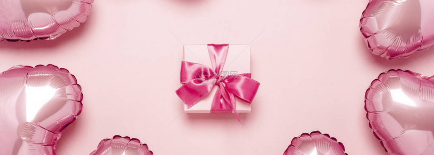 粉红色背景上心形的礼物和粉红色气球情人节装饰婚礼邀请或照片区的概念箔球横幅图片