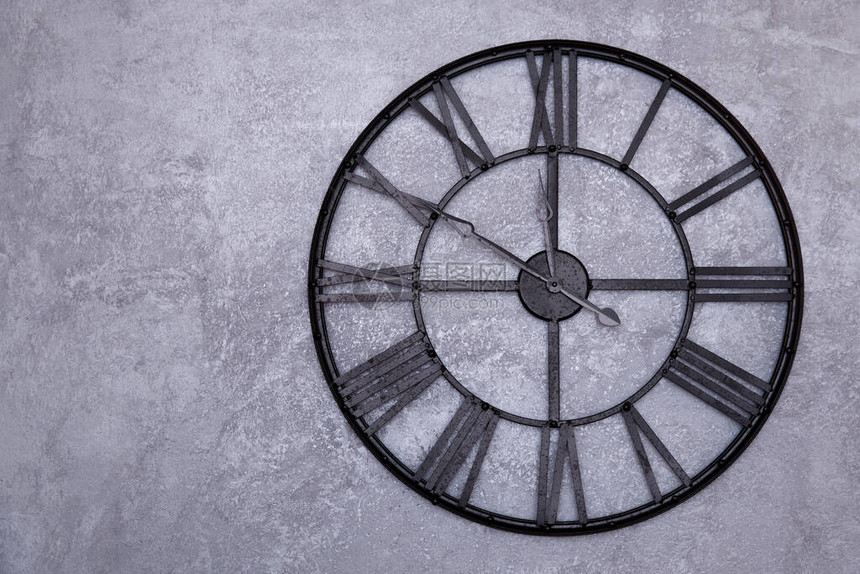 墙上有罗马数字的老式挂钟灰色的灰泥墙时钟显示十点到十二点图片