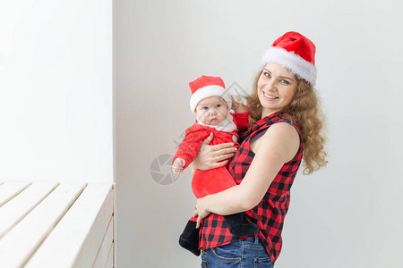 家庭童年和圣诞节的概念年轻的母亲穿着圣诞老人的衣服在图片