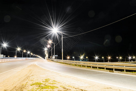 明亮的灯光和曝光线照亮的夜间高速公路有排气管的工厂月亮和星图片