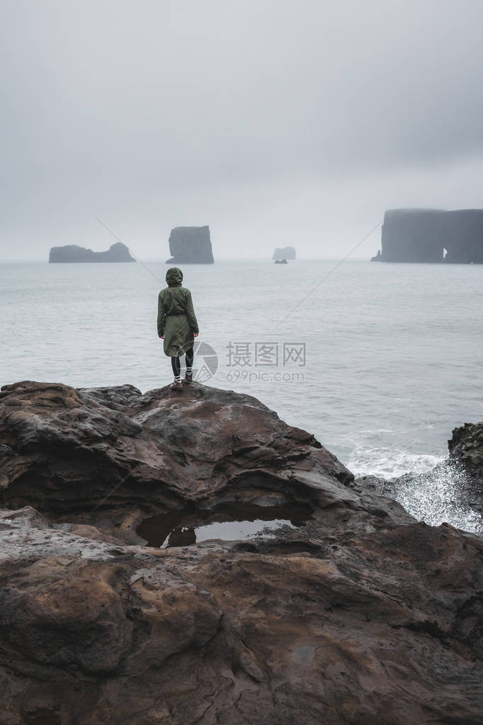 身着卡基夹克的人站在黑色火山石海滩上图片