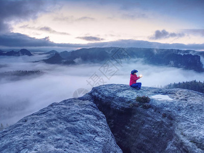 独身坐在山顶上的女孩喜欢在迷雾的海洋里坐船背景图片