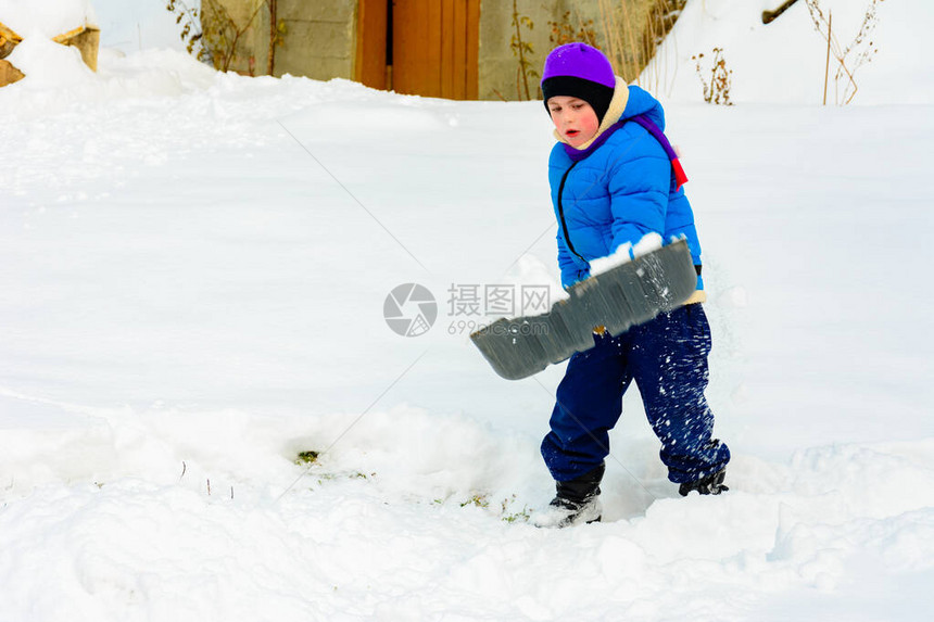 有大铲子的小男孩在暴风雪后除雪图片