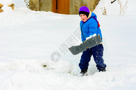 有大铲子的小男孩在暴风雪后除雪图片