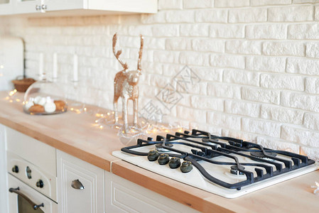 圣诞厨房里的炉子带有圣诞装饰的燃气灶白色厨房家具时尚的白色陶瓷砖墙图片
