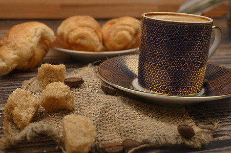 咖啡杯红糖羊角面包木制背景上的咖啡豆特写图片
