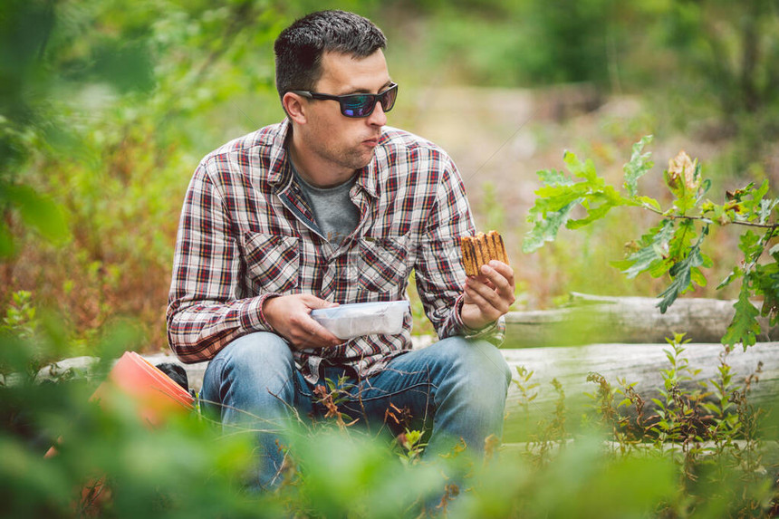 饥饿的人吃东西户外三明治的徒步旅行者坐在森林里吃三明治游客吃零食徒步旅行者休息时间吃饭白种人旅游带三图片