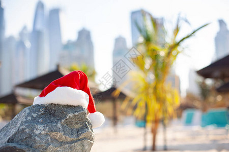 沙滩上的圣诞老人帽子俯瞰大海和美丽的迪拜市圣诞节和新年假期在温暖图片