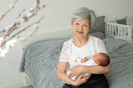 祖母很欣赏她可爱的孙女曾祖母和刚出生的曾孙女玩耍婴儿躺图片