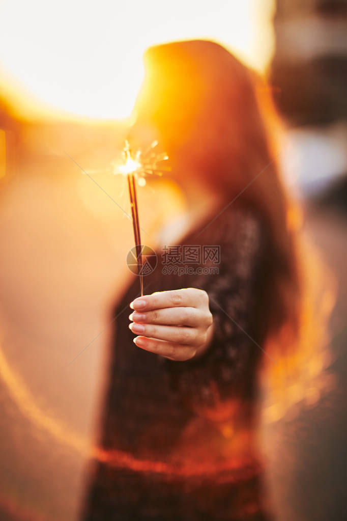 一个女孩手里拿着一个烟火新年图片